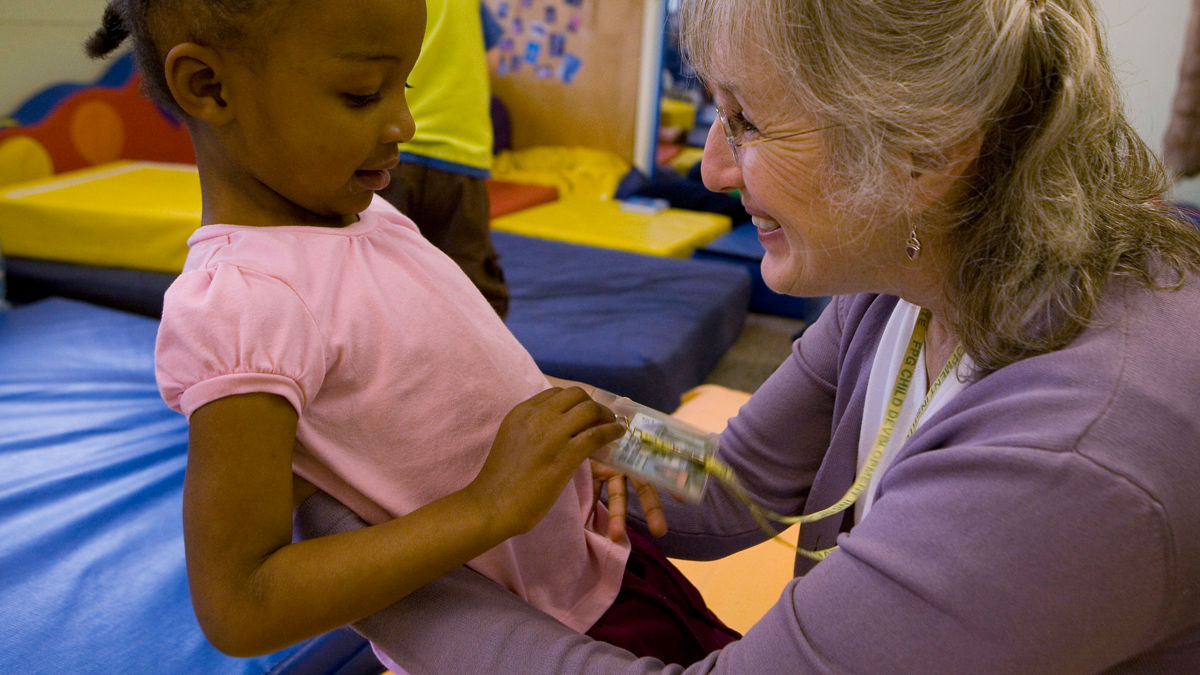 School director Maggie Connolly talks with Nariya Farrington in gross motor room.  Frank Porter Graham Child Development Center, Chapel Hill, North Carolina.