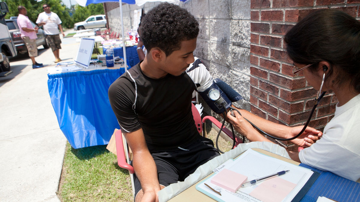 A medical professional checking a man's blood pressure.