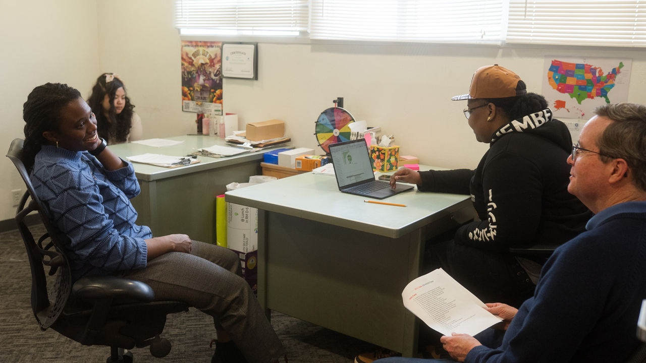 Sarah Michael Gaston, Deputy Director at Youth Forward, talks with community organizers, Araiye Thomas-Haysbert (Ray), 25, and Jen Phanh, 20, and Executive Director, Jim Keddy.