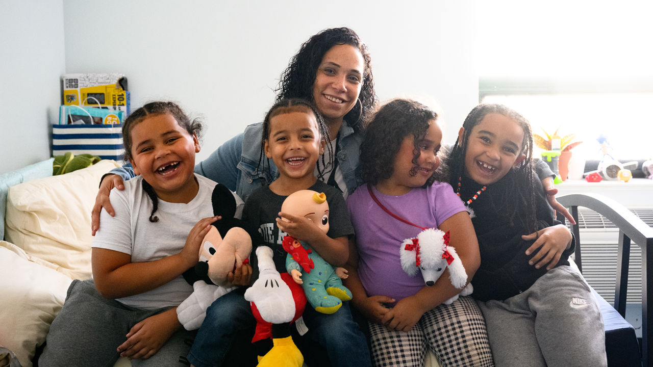 A mother siting on a bed for a portrait with her children.