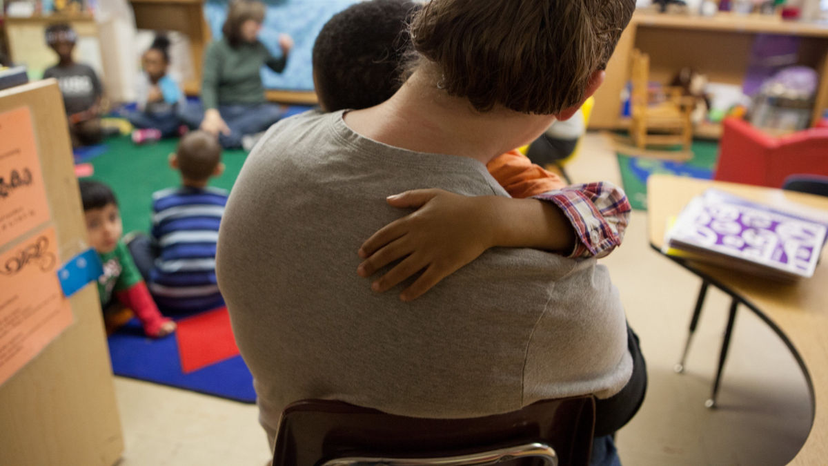 A teacher holding a student during class.