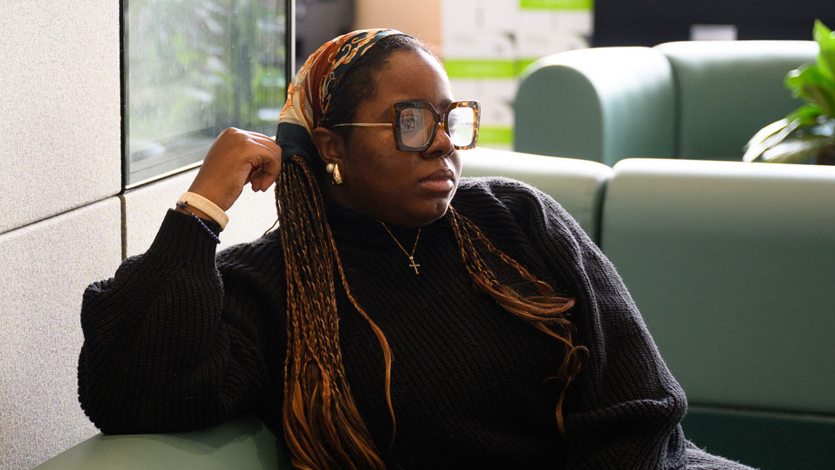 A woman wearing glasses sitting on a couch in a waiting room.