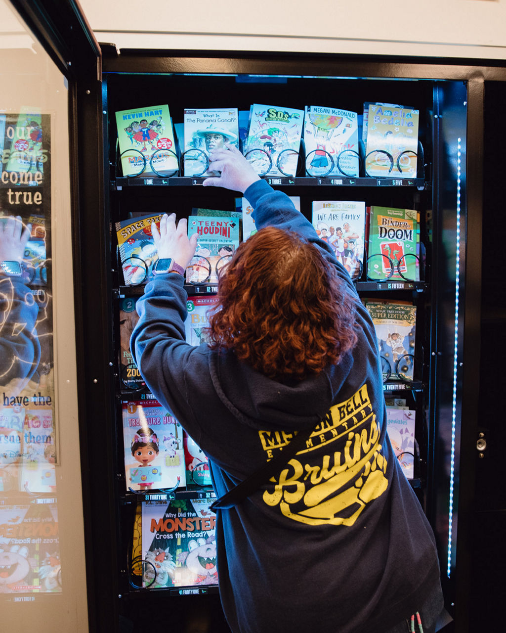 A librarian organizes books inside of a book vending machine. 