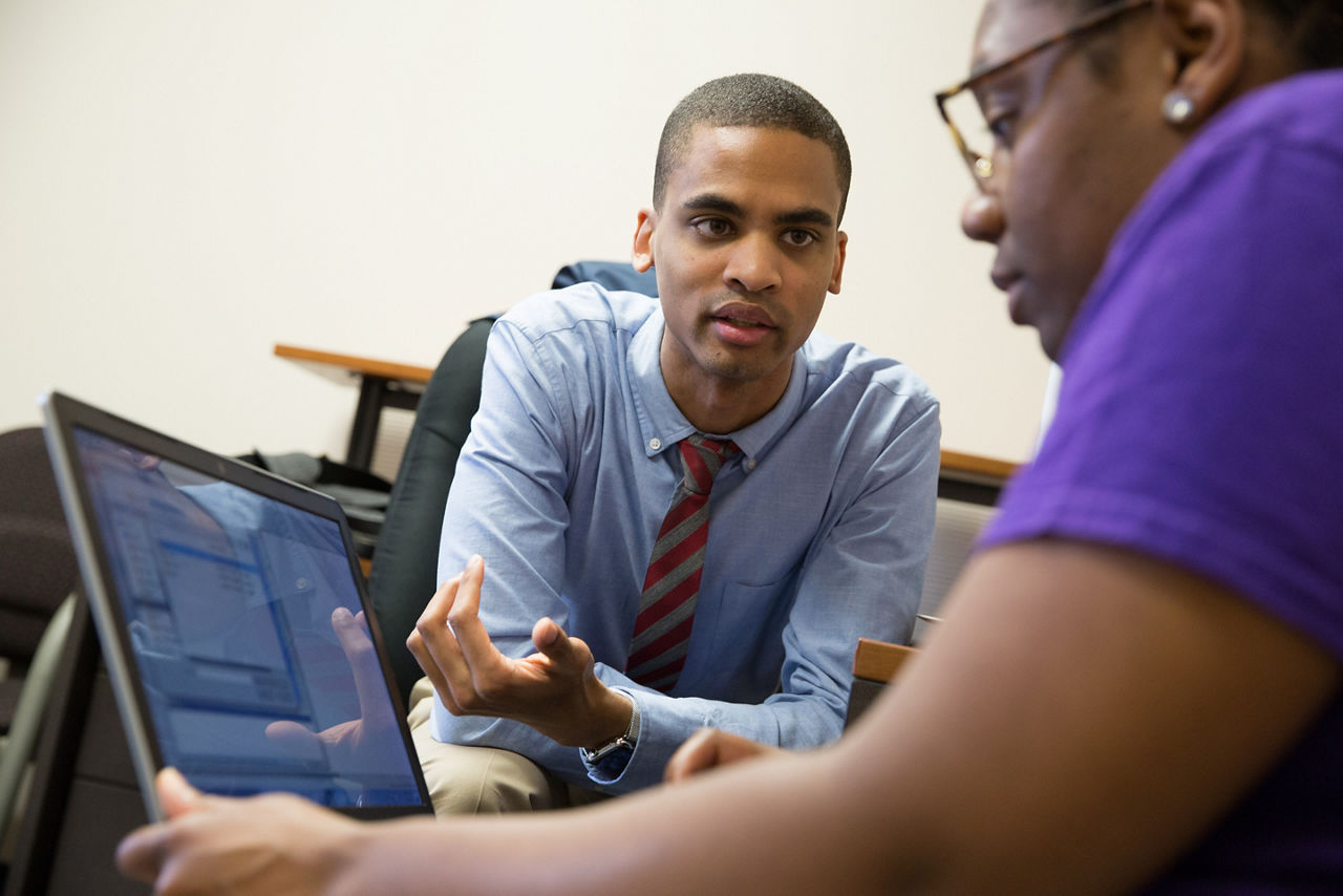 A man and woman go over research findings on a computer monitor.