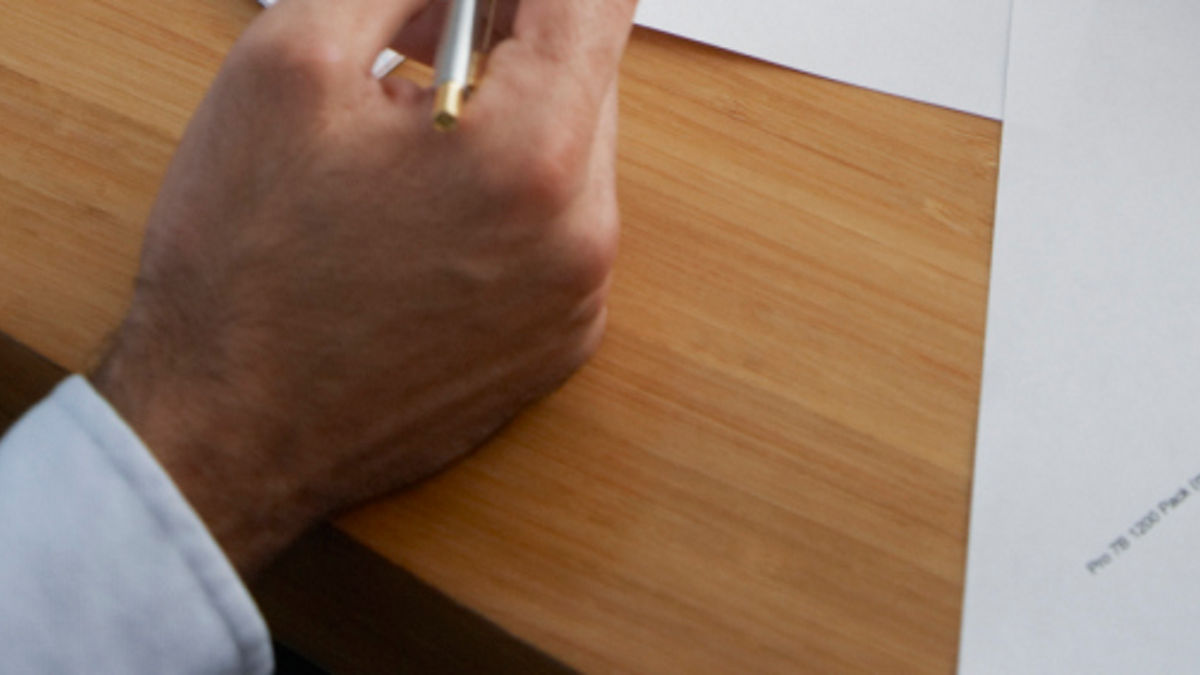 Four business people's hands at a boardroom table