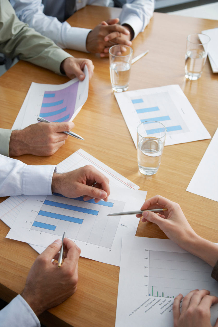 Four business people's hands at a boardroom table