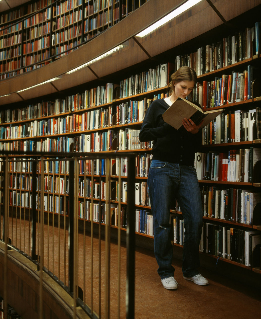 A woman reading a book in a library.