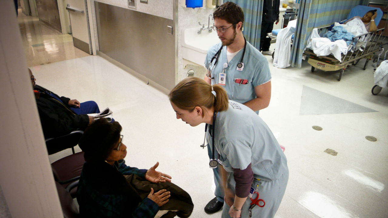 Health professionals talking with a patient in a hospital.