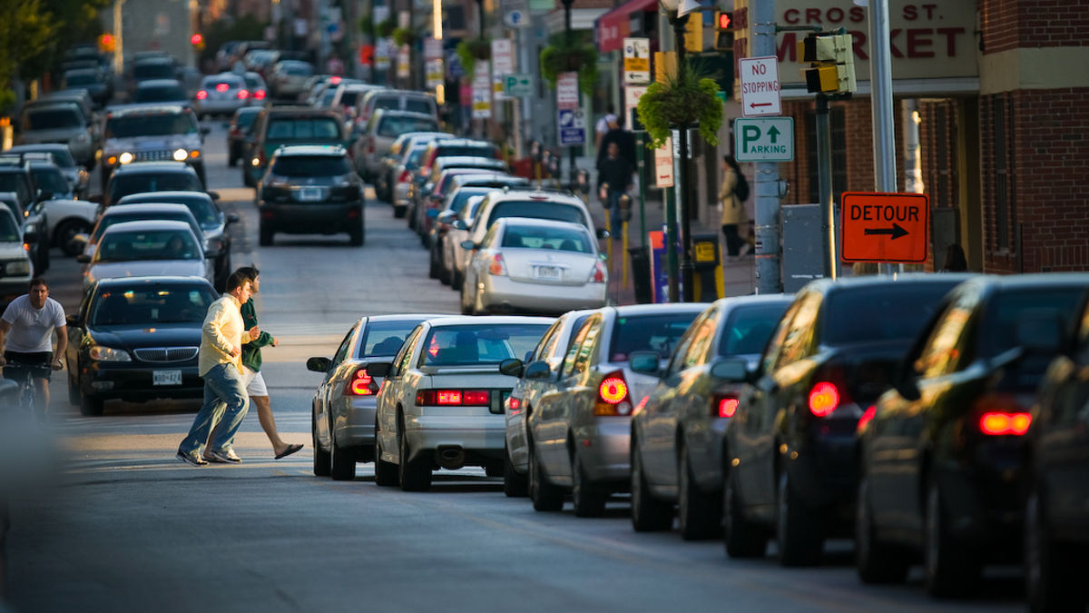 Streets with parked and moving cars and buildings in  Baltimore, Maryland.