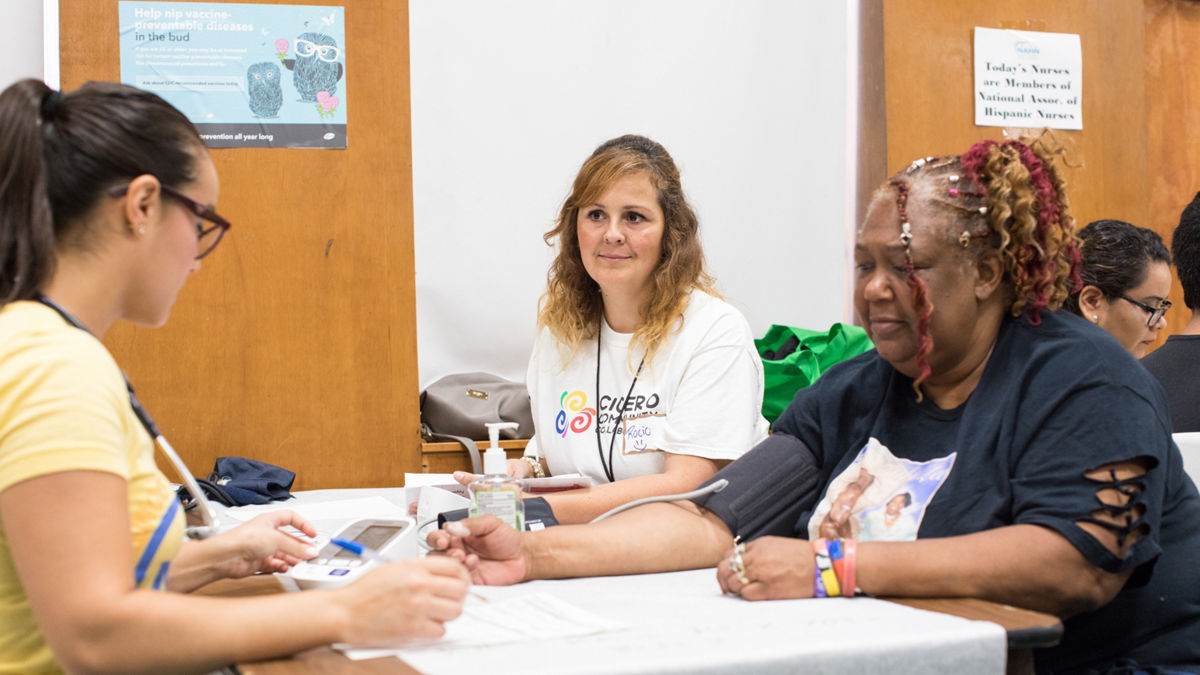 Three women talking at a table at a health fair.