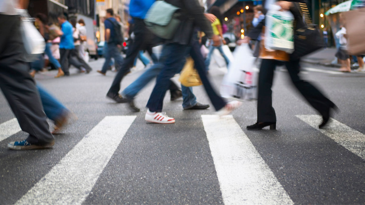 Pedestrians crossing the street within a city crosswalk.