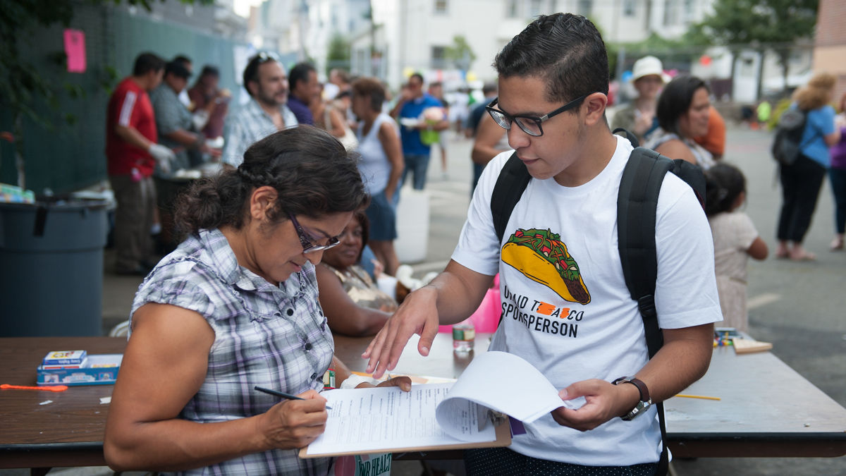 Gustavo Castilho, a member of Teens in Everett Against Substance Abuse, surveys one of the guests at the One Everett block party. Culture of Health - Prizewinners - Everett, MA