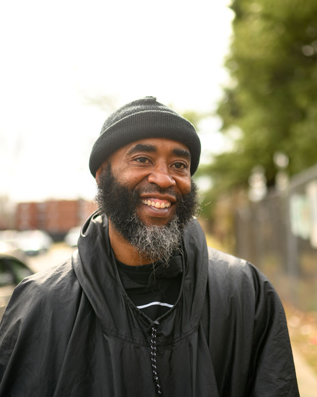 A man standing for a portrait during a  street restoration outreach event.