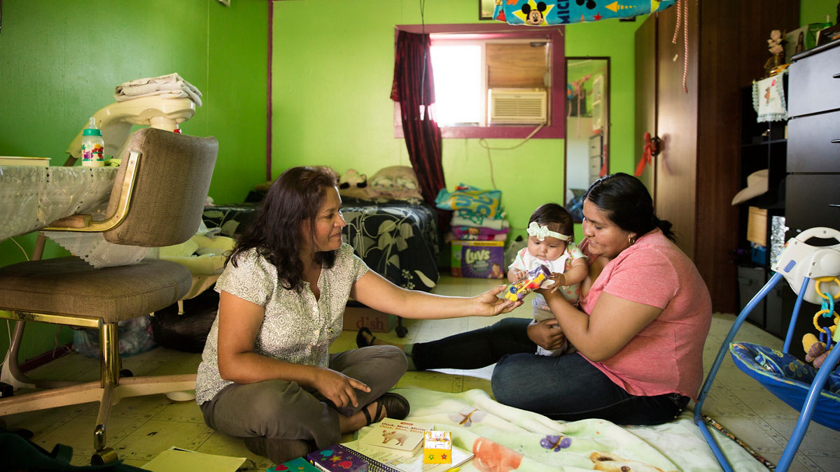 Two women caring for a infant at home.