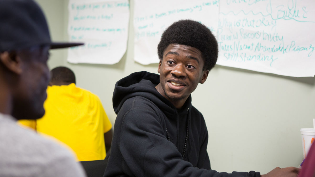Two young adult students talking in a classroom.