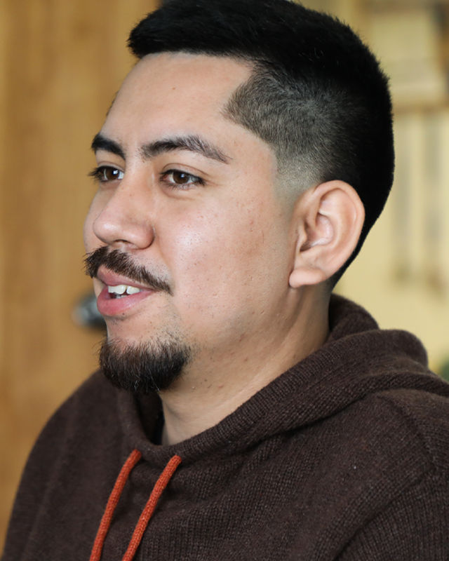 A person with a mustache and beard poses for the camera.