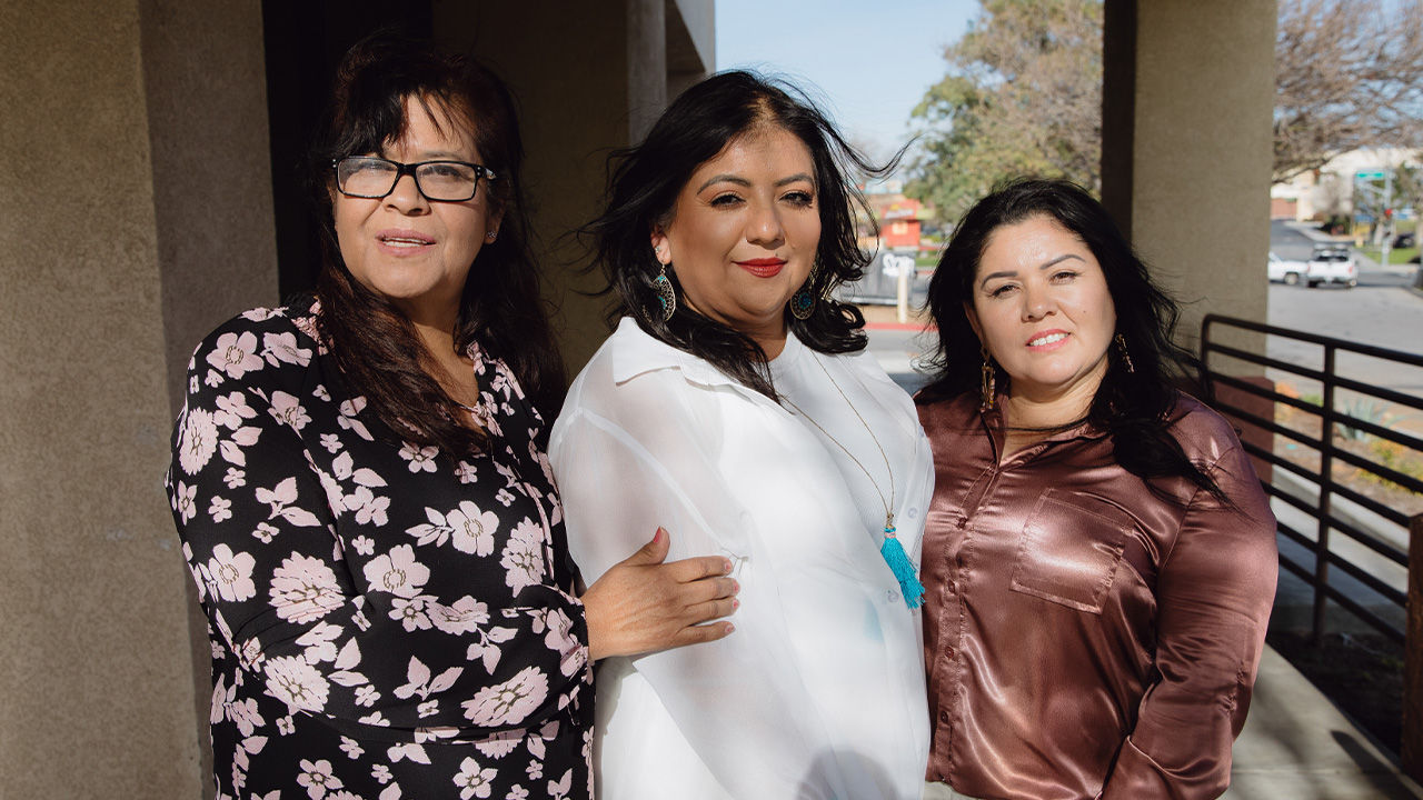 Three women—community leaders—pose for a portrait.