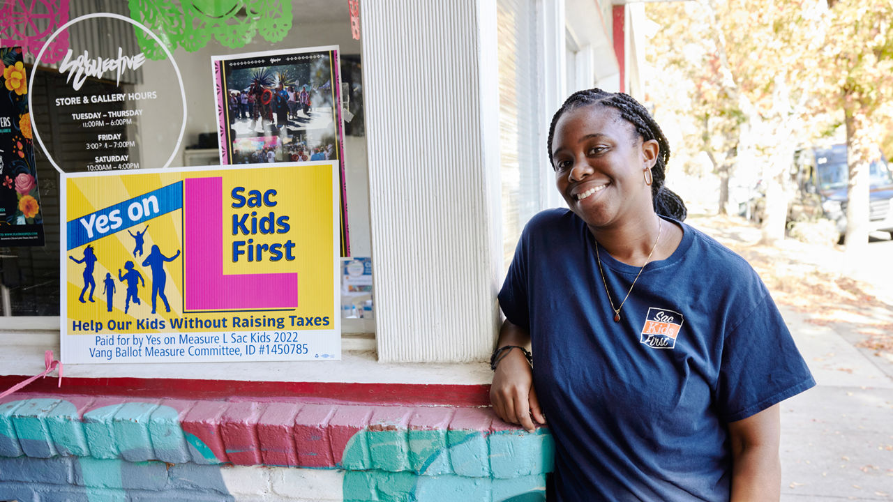 A woman poses next to a youth program poster.