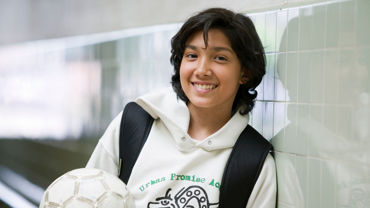 Sports 4 Kids junior coach Christian Olivales in the hallway of Urban Promise Academy, Oakland, California.  Sports 4 Kids (Playworks)