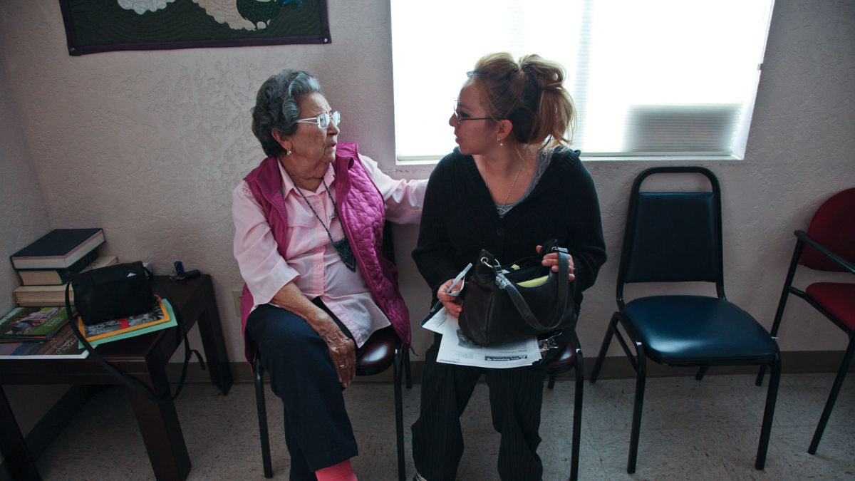 A woman and her daughter filling out forms in a doctor's office waiting room.