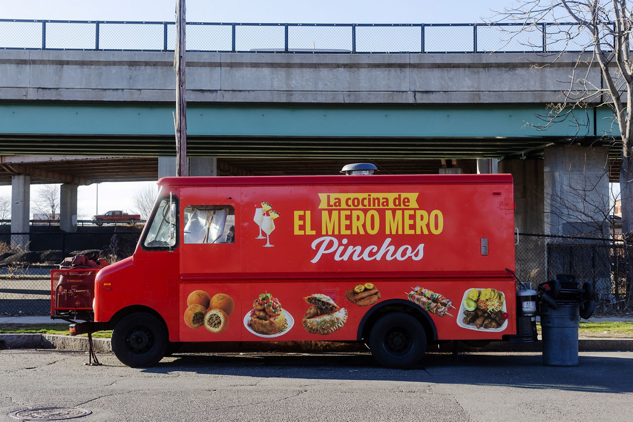 A food truck parked under an overpass.