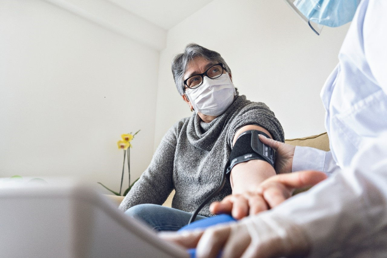 A nurse takes a patient's blood pressure during a medical home visit.