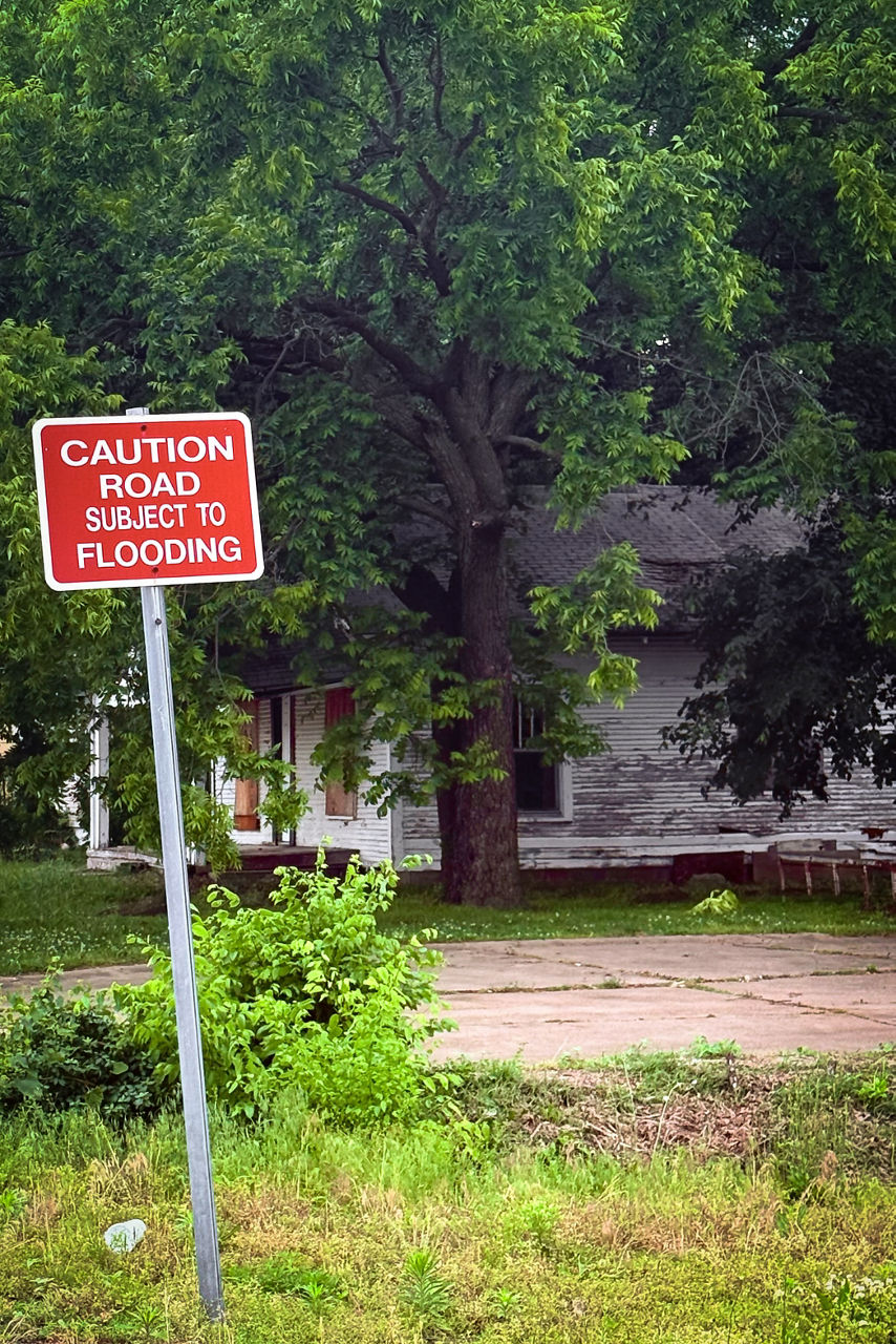 A red street sign warning people of a road that is subject to flooding. 