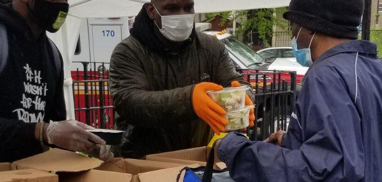 Men wearing protective masks distribute food.