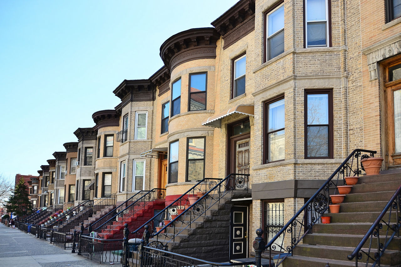 Row homes with wrought iron hand rails against a blue sky.
