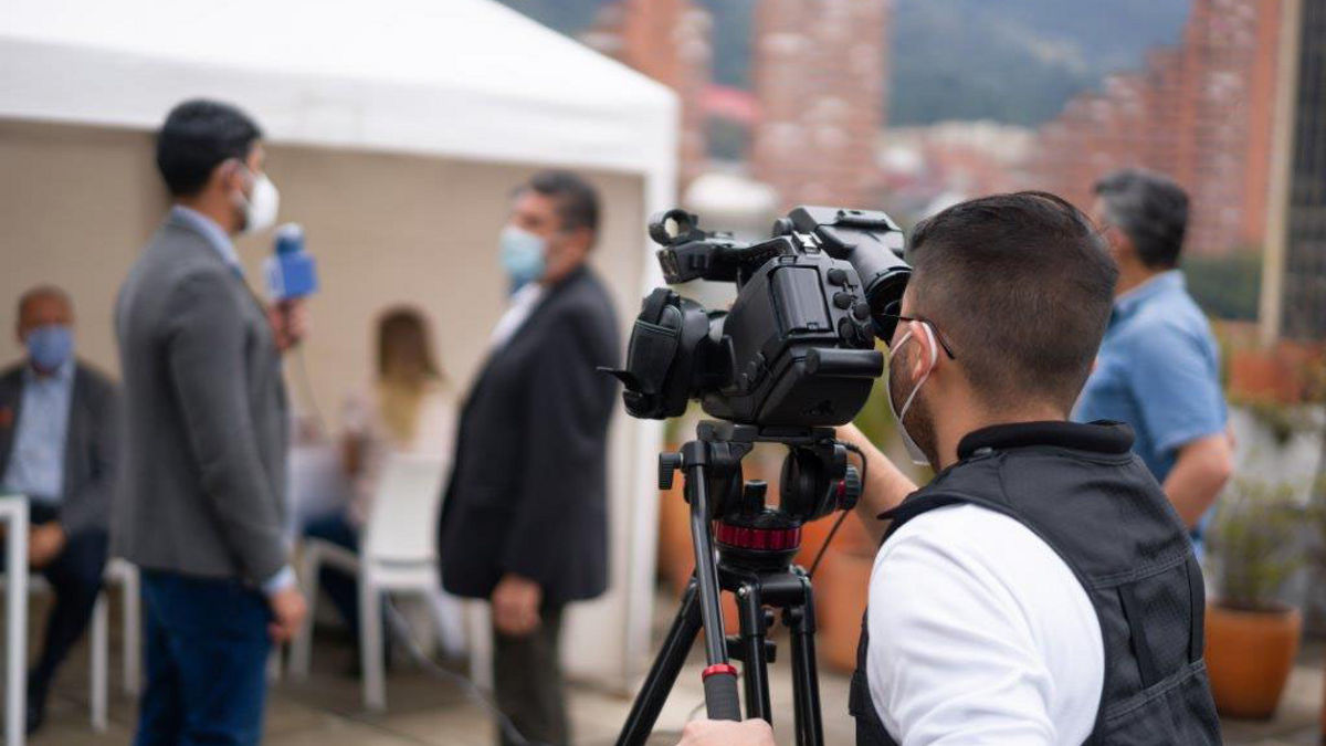 A cameraman recording the latest news from a COVID-19 vaccination stand.