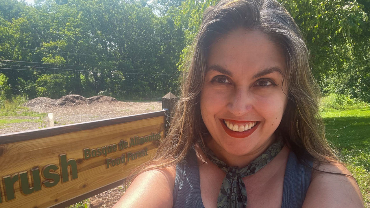Cassandra Vogl taking a selfie in front of a wooden sign.