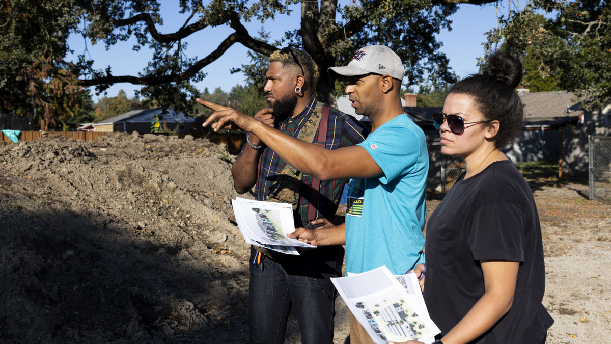 Three people standing outside with space planning paperwork in their hands.