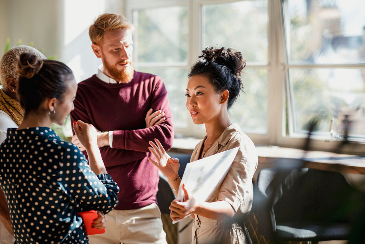 Colleagues standing together in group talking.