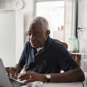 A senior man working at a laptop.