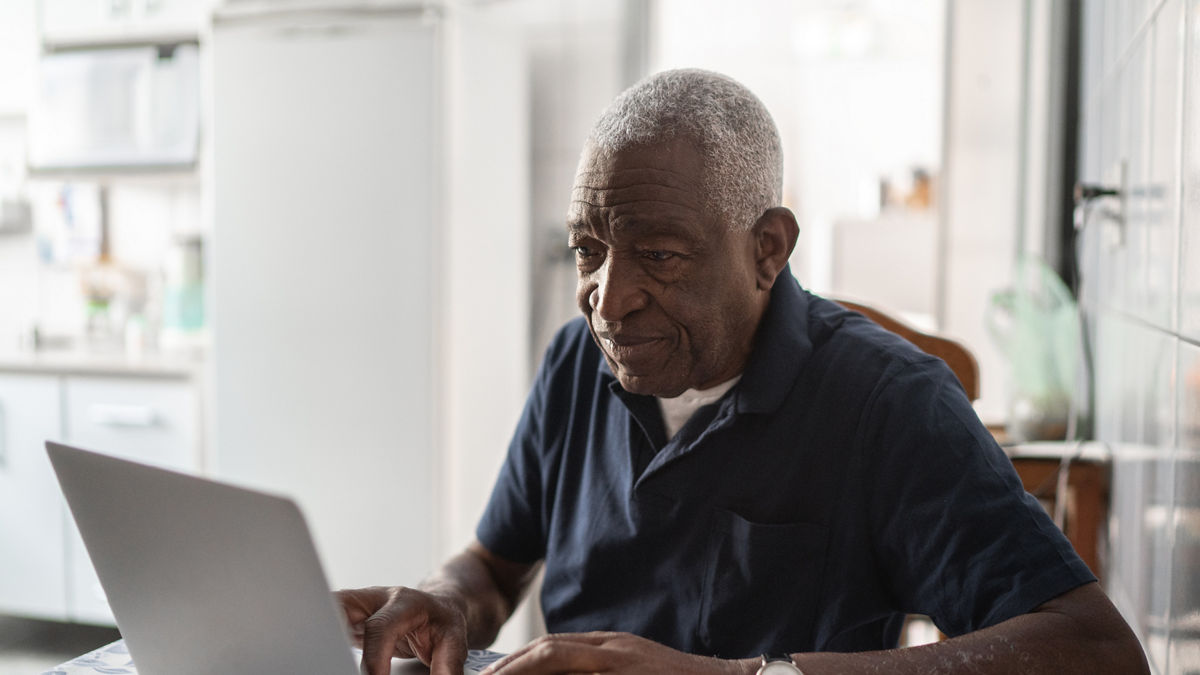 A senior man working at a laptop.