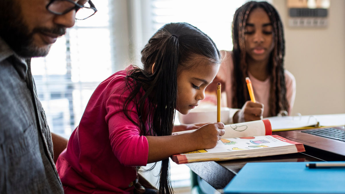Father working from home while daughters homeschool