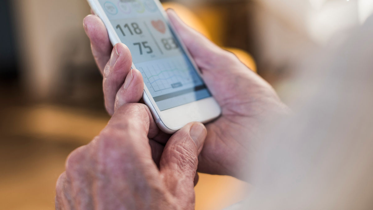 Male hands holding smartphone, checking blood pressure, heart rate with obscured other body parts.