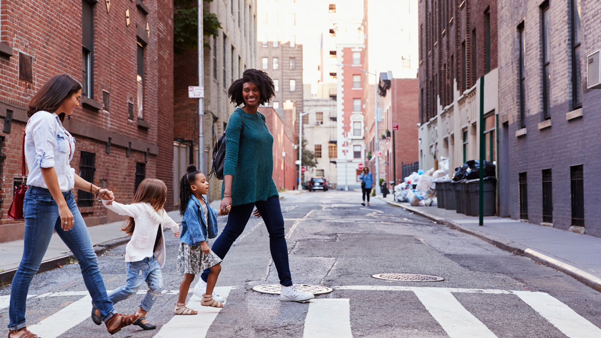 Two women and their daughters crossing a street.