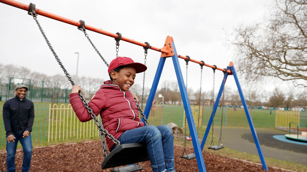 Father and son playing on the swings in the park