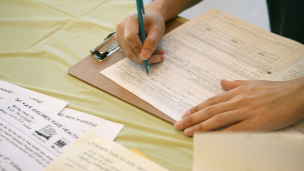 A man fills out an application for SCHIP (State Children's Health Insurance Program) at a Covering Kids &  Families enrollment event. Covering Kids & Families