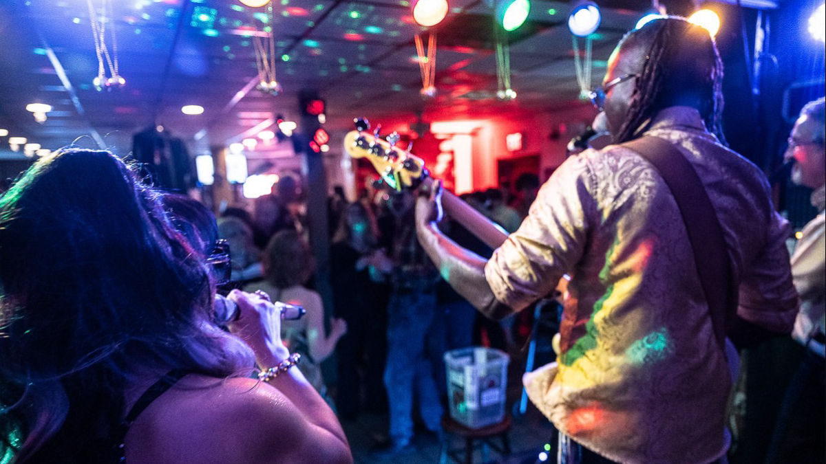 A musician playing with bandmates at a club. 