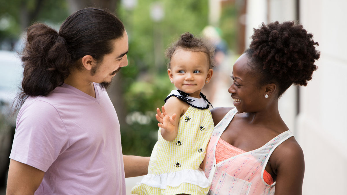 A smiling family standing on a city street.