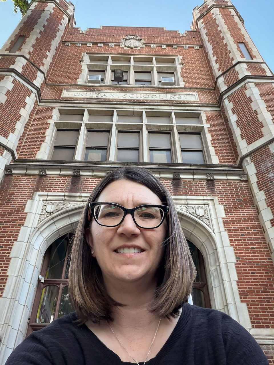A photo of Kerry in front of a large, brick school.