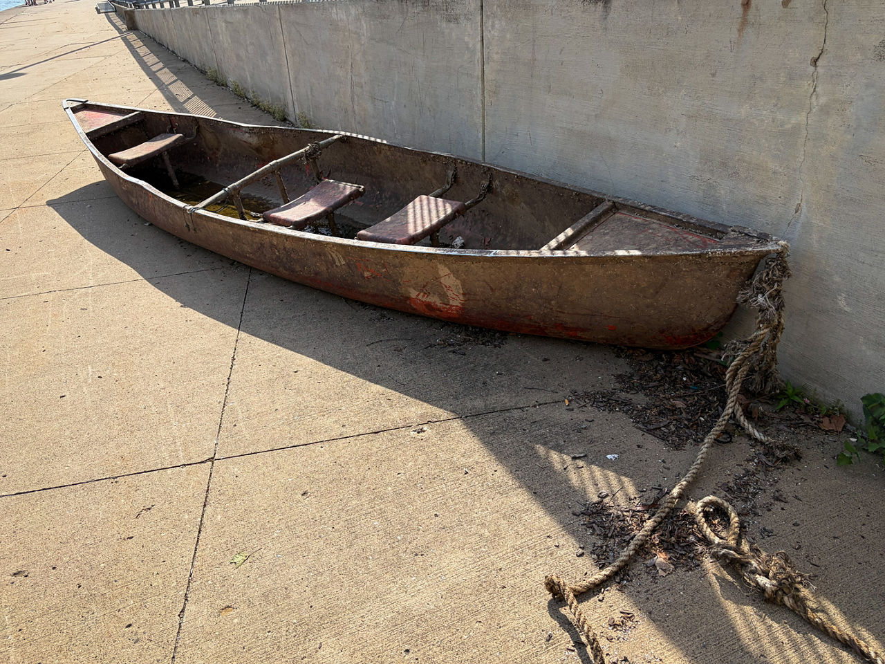 A rowboat pictured on concrete pavement.