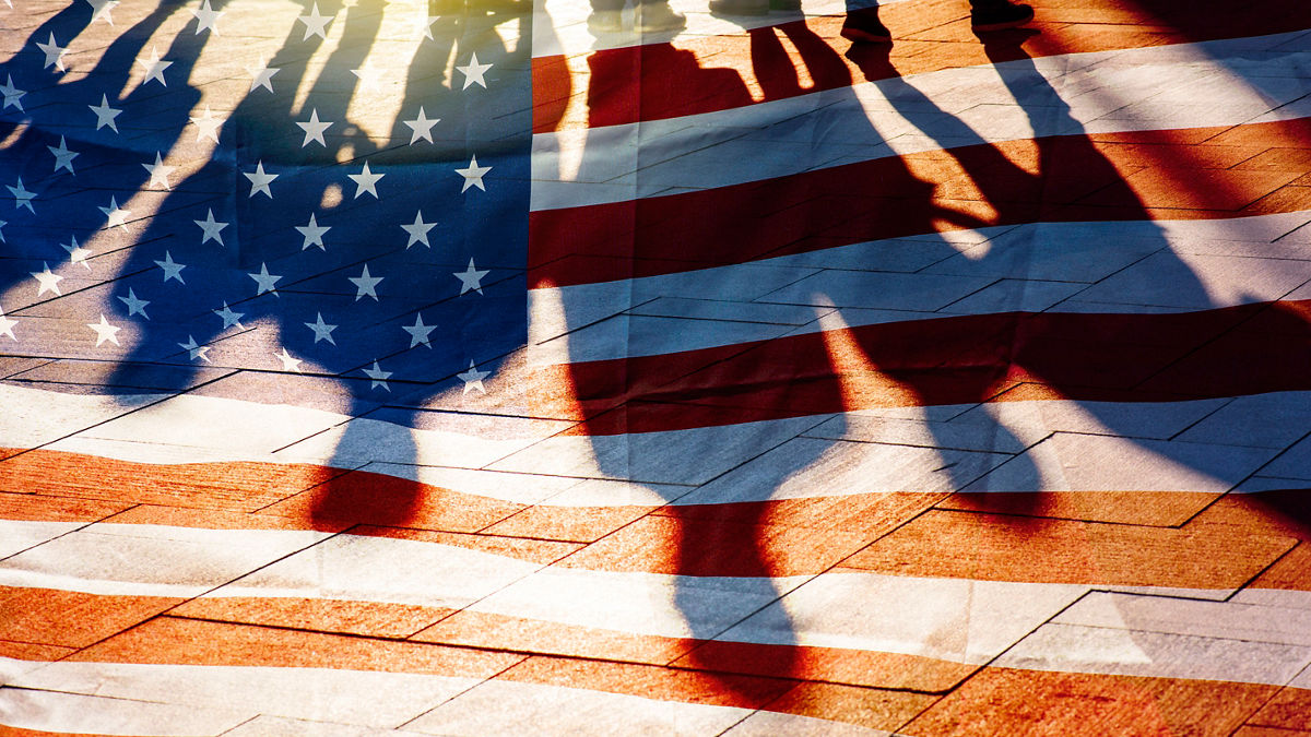 Shadows cast against an American flag, highlighting the concept that some people exist, but are often not fully seen. 