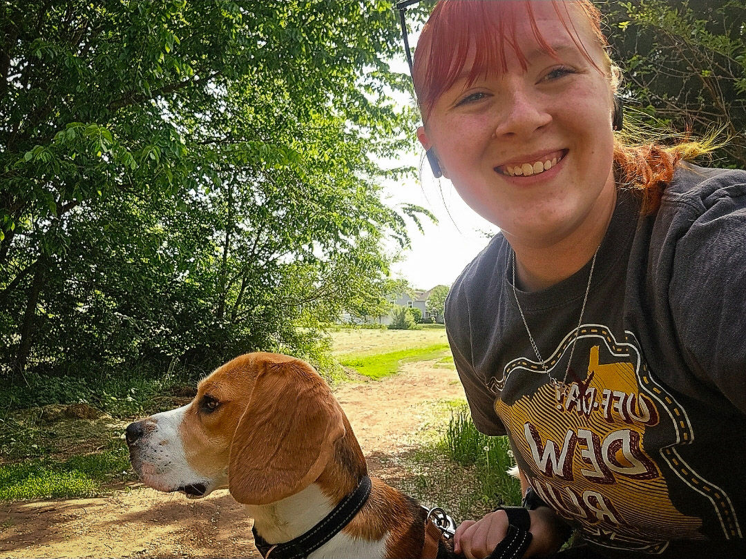 Maya and her dog on a walking path in the woods.