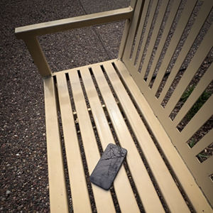 A cell phone that has been left on a park bench.