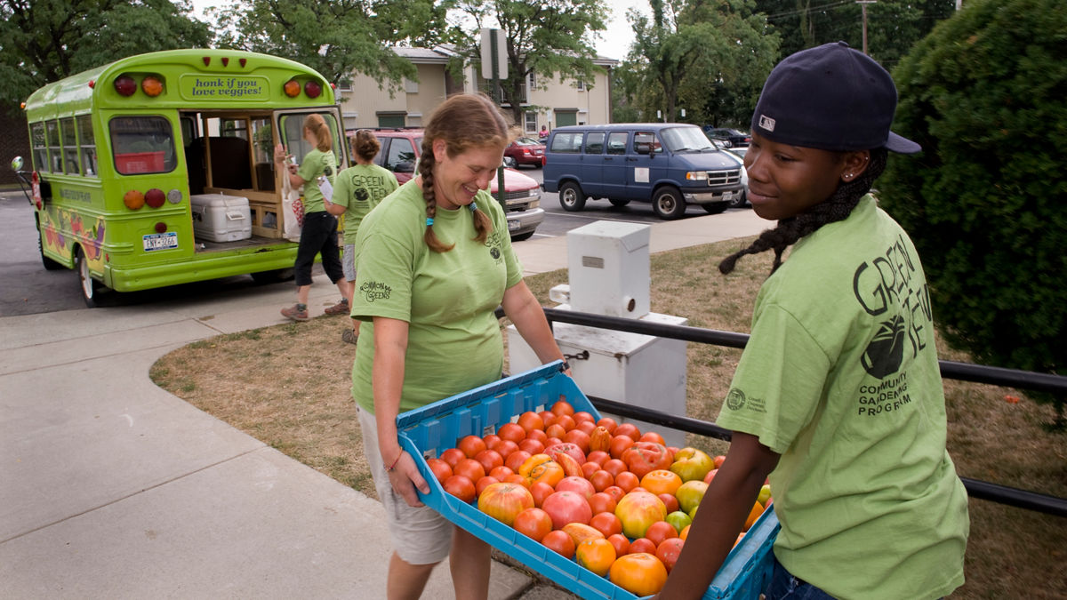 High school students carrying a bin of produce.