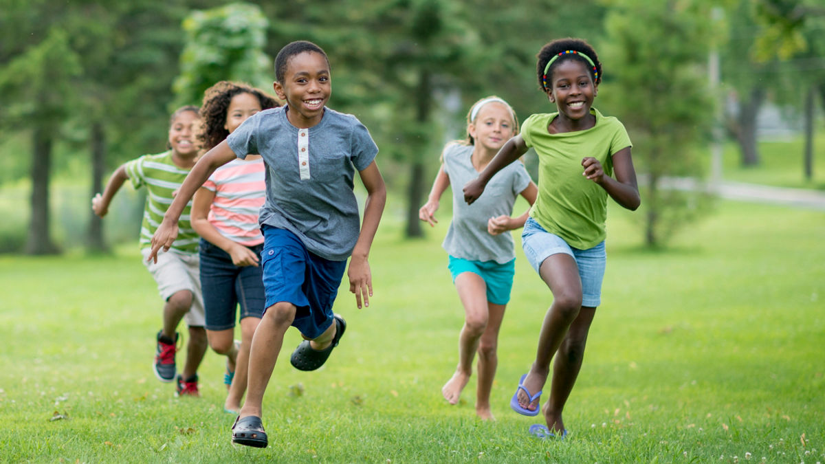 Boys and girls running and playing in a park.