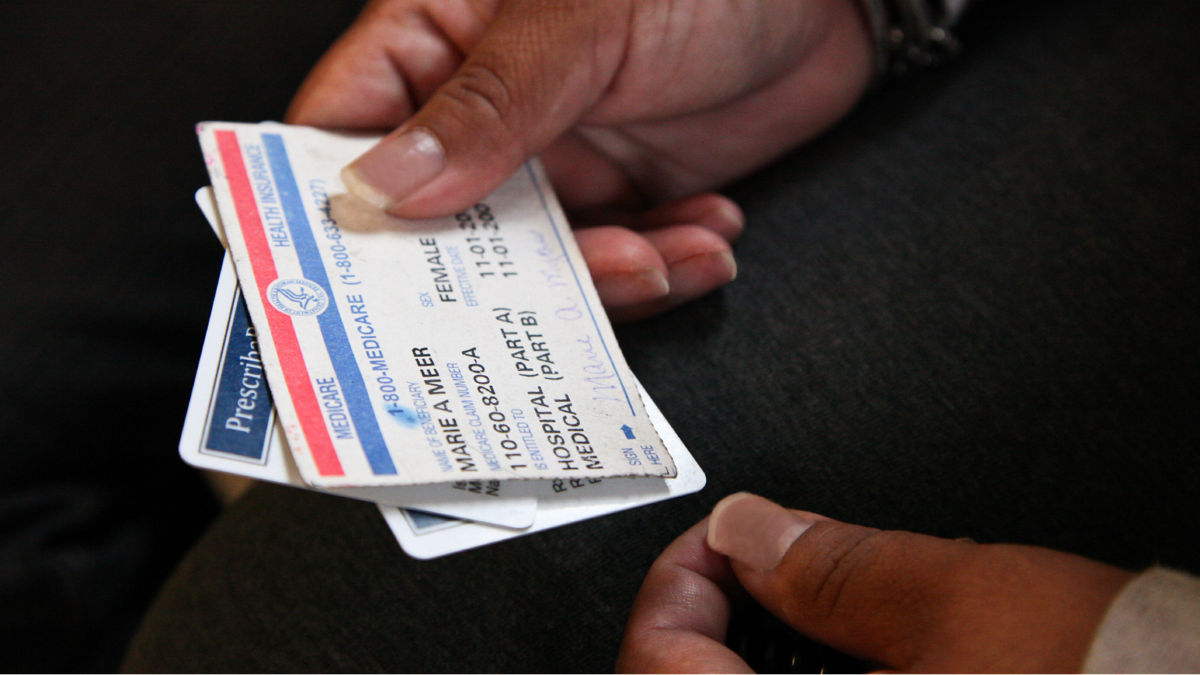 A woman holds medical insurance cards.